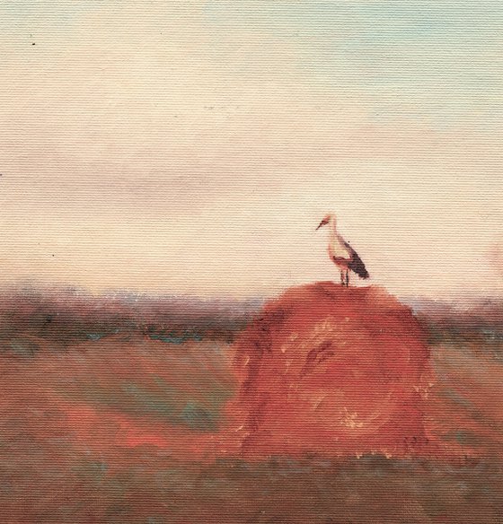 Stork on a haystack, in frame