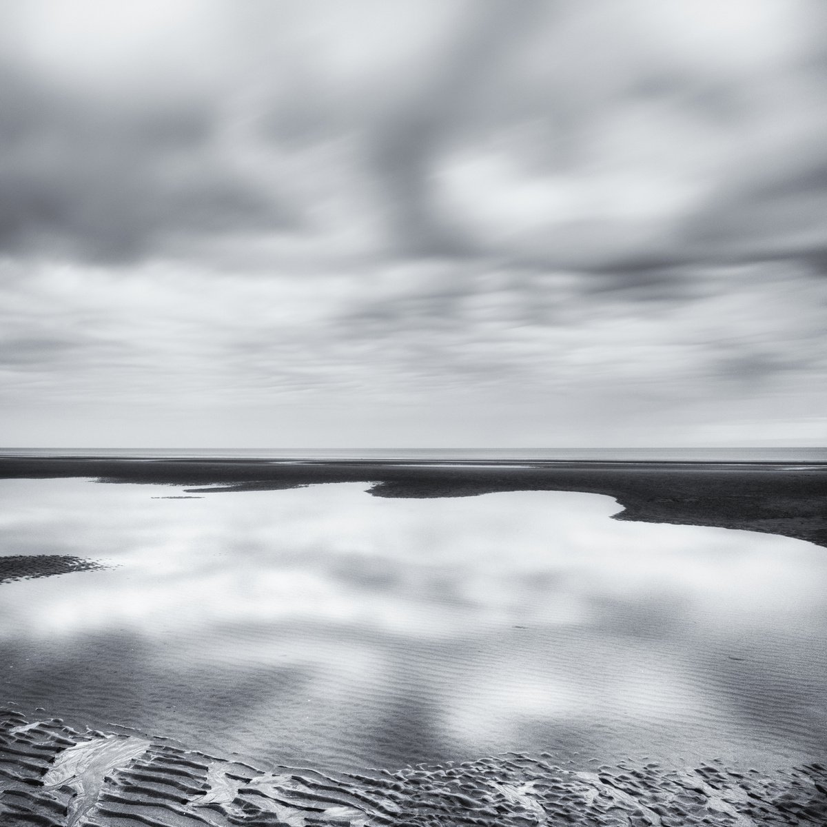 Low tide and reflected clouds by Karim Carella