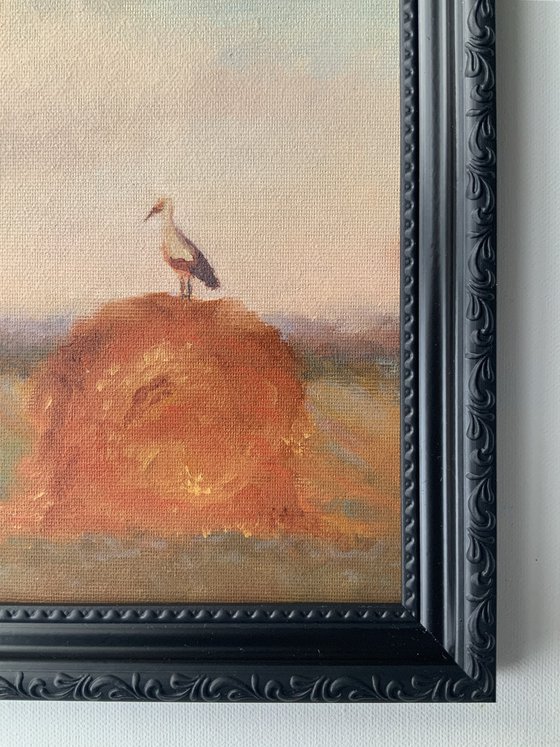 Stork on a haystack, in frame