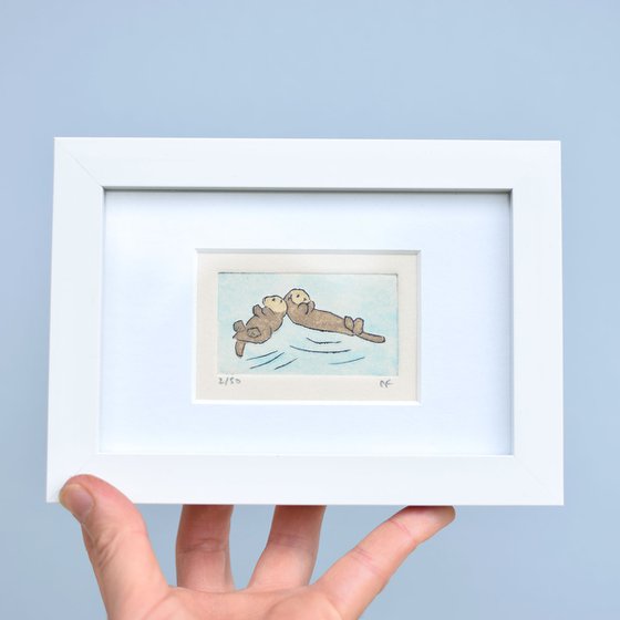 Small framed two sea otters touching heads