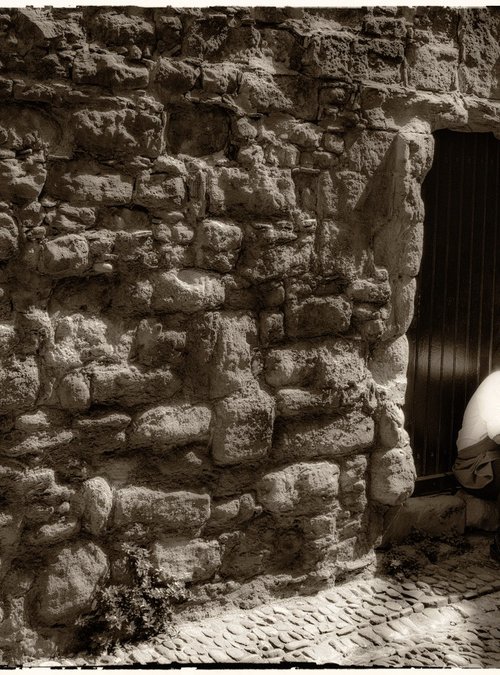 man smoking by old stone wall by Daniel Fontaine
