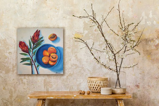 Protea flowers and apricots on blue plate