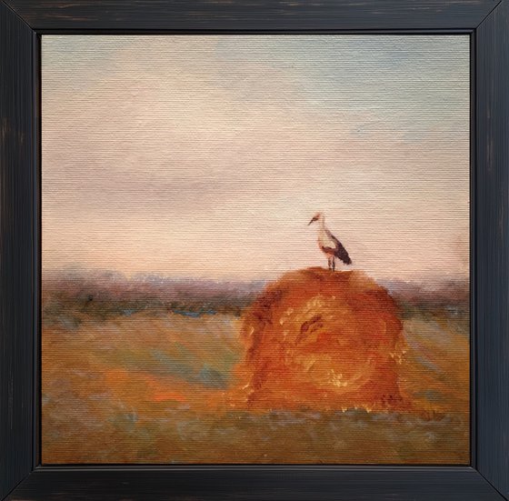 Stork on a haystack, in frame