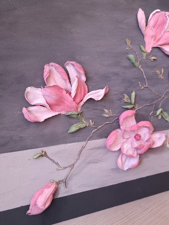 Pink Magnolia on a gray background. Relief still life with a branch of large flowers in a glass vase. Spring blooming