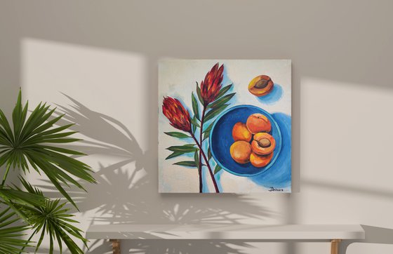 Protea flowers and apricots on blue plate