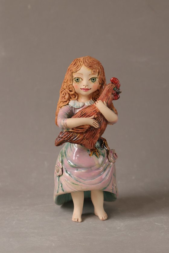 Vintage dressed girl holding a chicken.