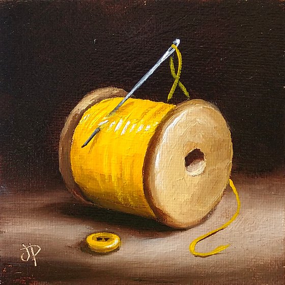 Little yellow cotton reel with button still life