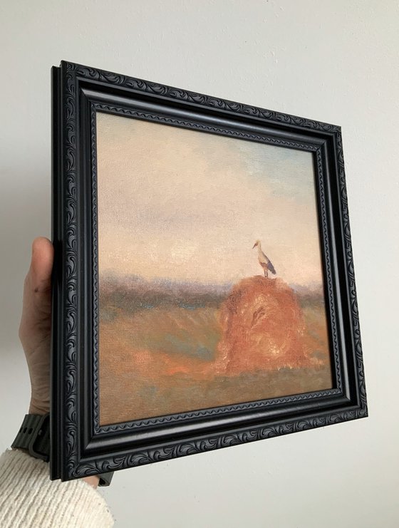 Stork on a haystack, in frame