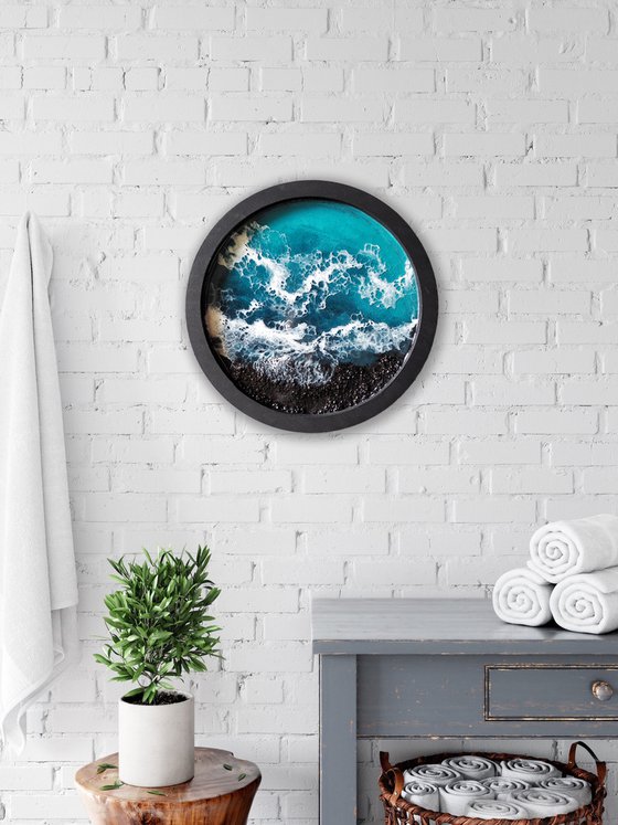 Round window overlooking the sea in a black frame