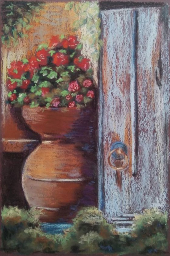 Pot with geraniums at the old door