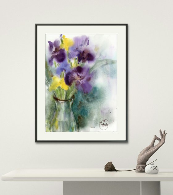 Bouquet of purple and yellow irises in a glass vase.