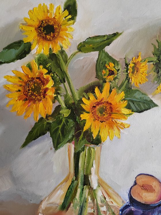 . Yellow sunflower bouquet in glass vase with plums in a porcelain bowl still life