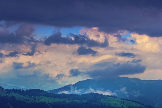 Waves of clouds over green mountains.