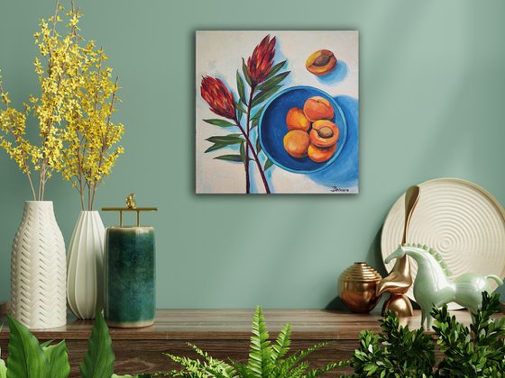 Protea flowers and apricots on blue plate