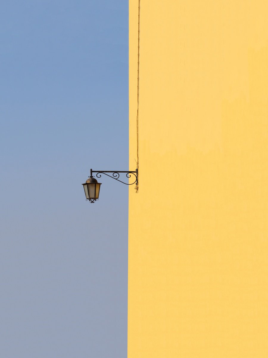 SIngle lamp on yellow wall by Marcus Cederberg