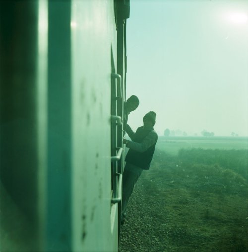 Travellers hanging off train by Nadia  Attura