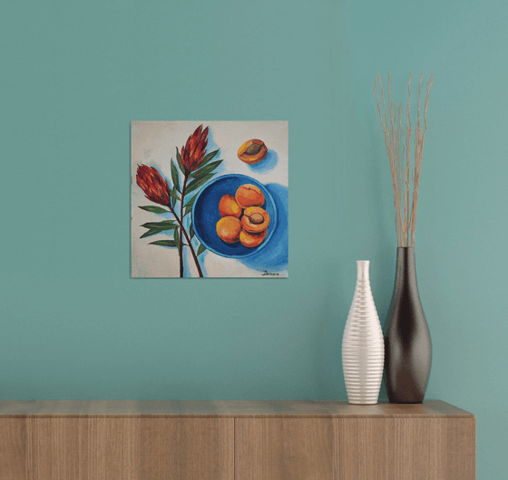 Protea flowers and apricots on blue plate