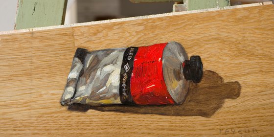 modern still life of a red color painting tube on a plank board