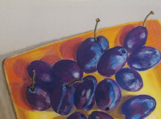 Blue plums on a yellow dish