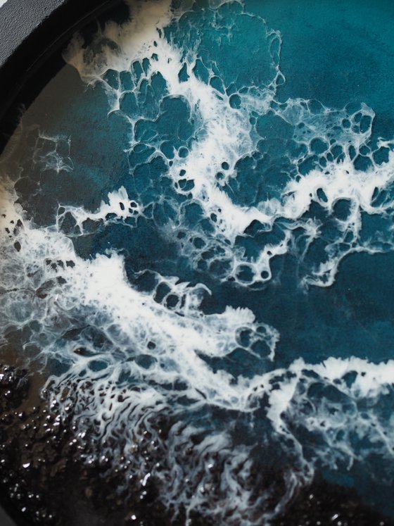 Round window overlooking the sea in a black frame