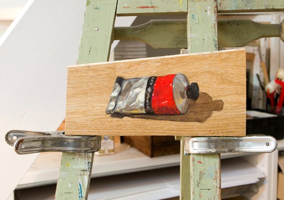 modern still life of a red color painting tube on a plank board