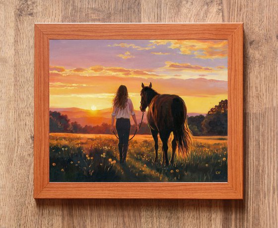 Woman walking with a horse in a sunset field