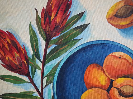 Protea flowers and apricots on blue plate