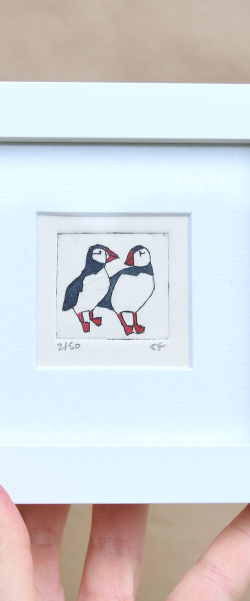Mini framed two puffins standing close and looking at each other by Sally Fisher