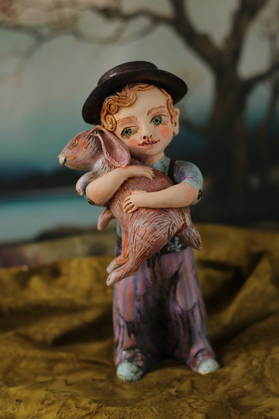 Vintage dressed boy holding a rabbit.