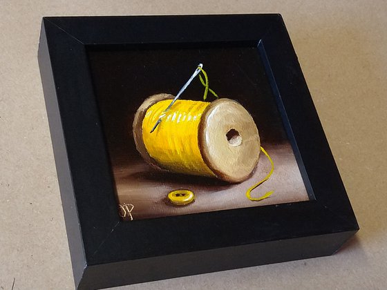 Little yellow cotton reel with button still life