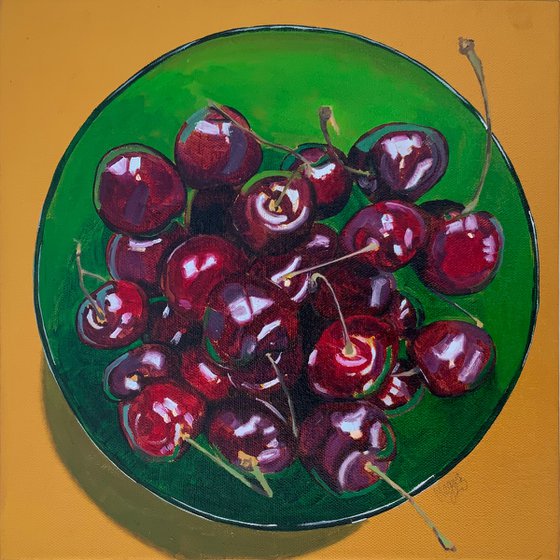 Cherries in a green glass bowl against a gold background