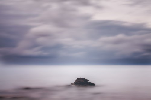 A lone rock in the silky sea by Karim Carella