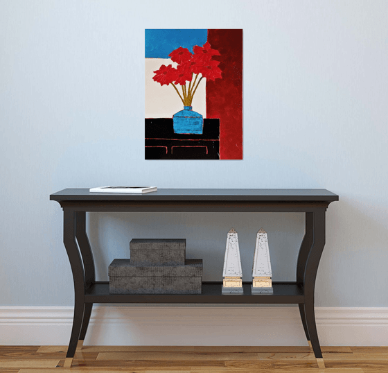 RED FLOWERS IN AN OLD BLUE VASE ON A BLACK CREDENZA