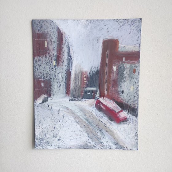 Red car and red houses. It`s snowing. Snow landscape