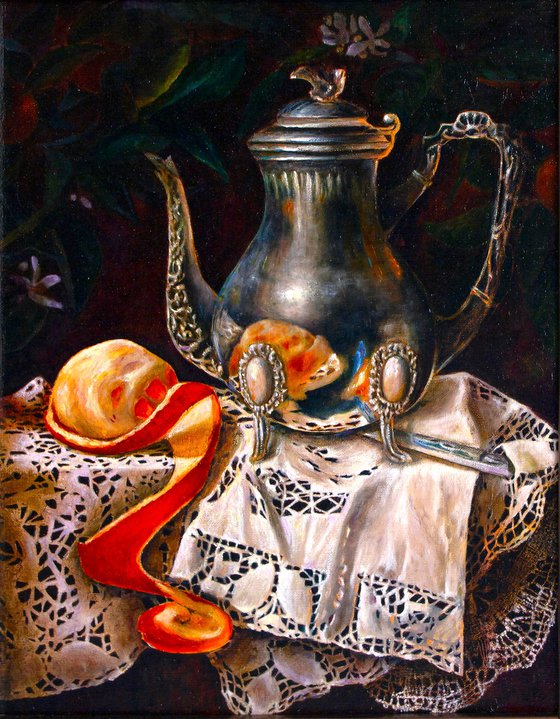 Silver coffee pot with orange on a linen tablecloth