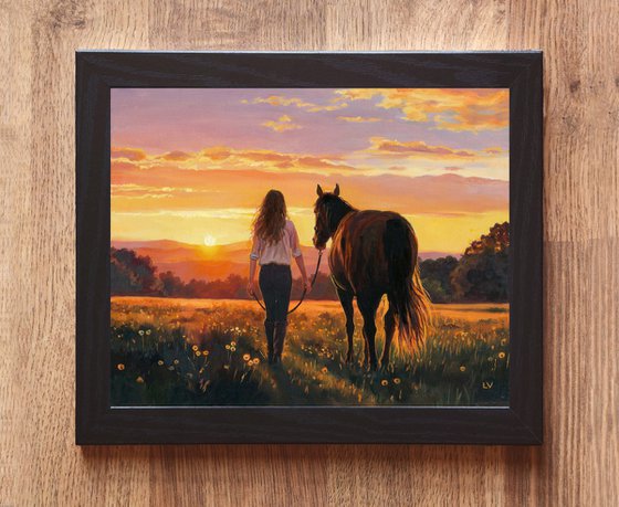 Woman walking with a horse in a sunset field