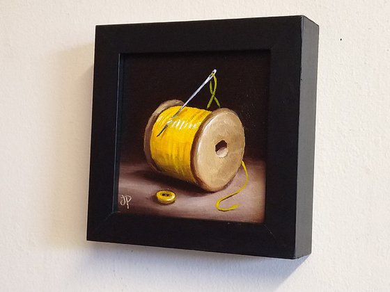 Little yellow cotton reel with button still life