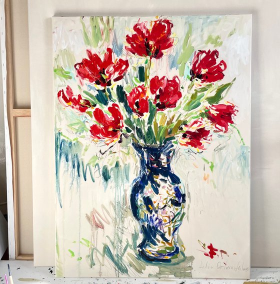Red tulips in a blue vase.