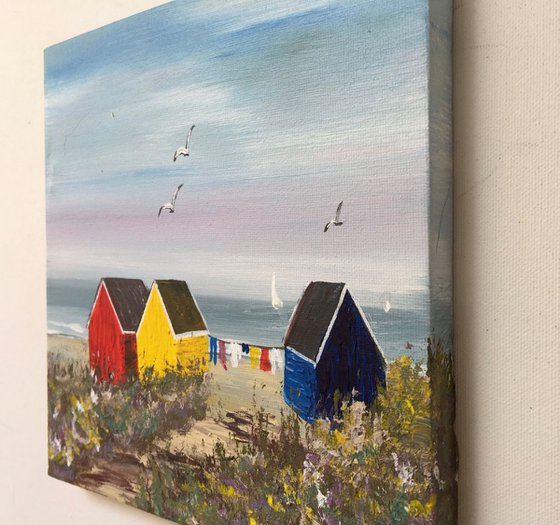 Three beach huts on the beach on a square canvas