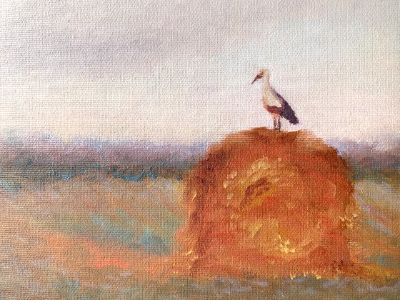 Stork on a haystack, in frame