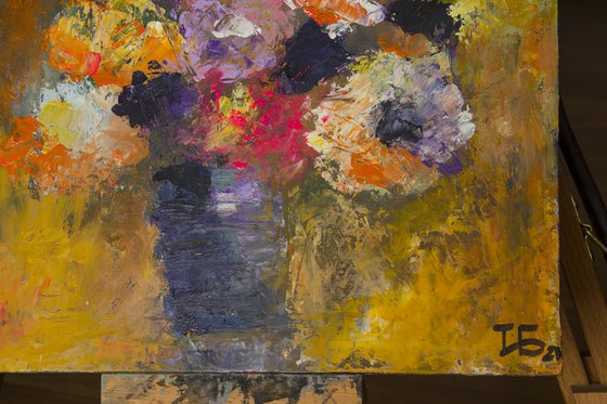 Small still life with bright flowers in the lilac vase on orange background