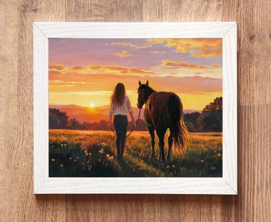 Woman walking with a horse in a sunset field