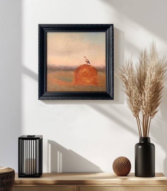 Stork on a haystack, in frame