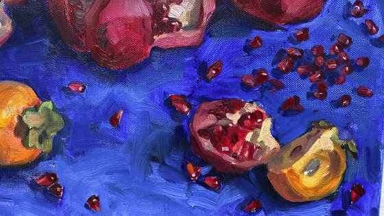 Pomegranates and persimmons on blue