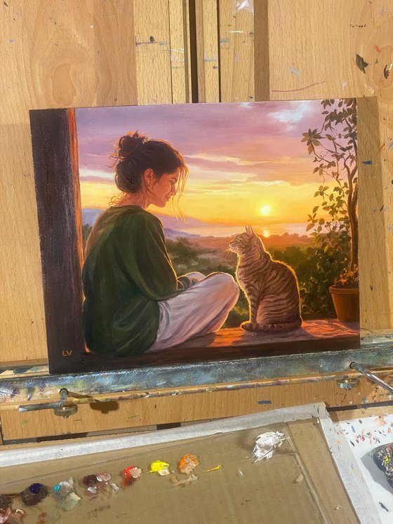Girl watching the sunset with her tabby cat