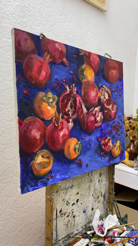 Pomegranates and persimmons on blue