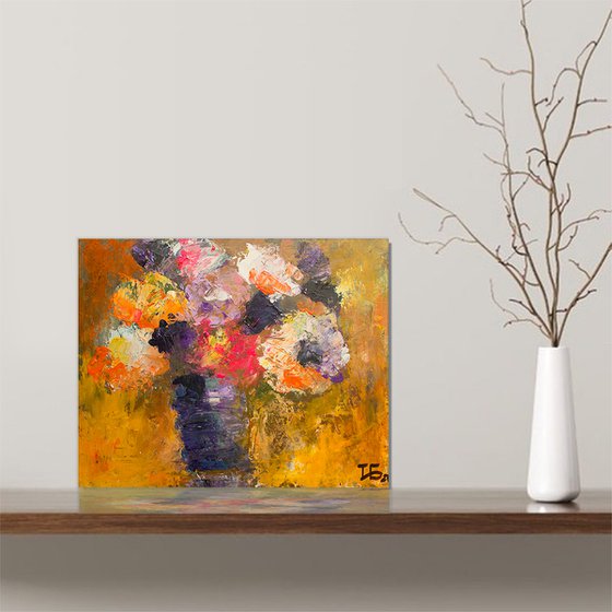 Small still life with bright flowers in the lilac vase on orange background
