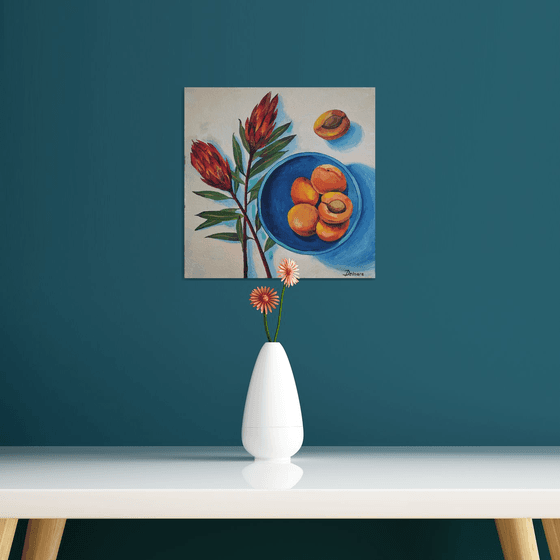 Protea flowers and apricots on blue plate