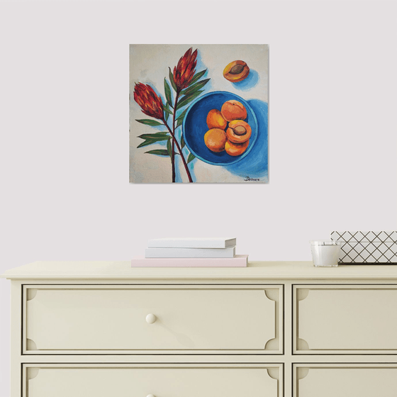 Protea flowers and apricots on blue plate