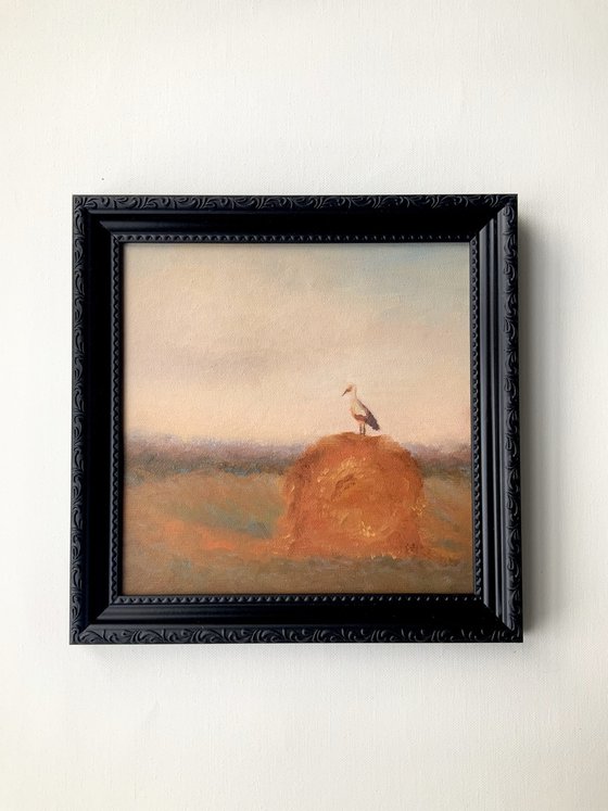 Stork on a haystack, in frame